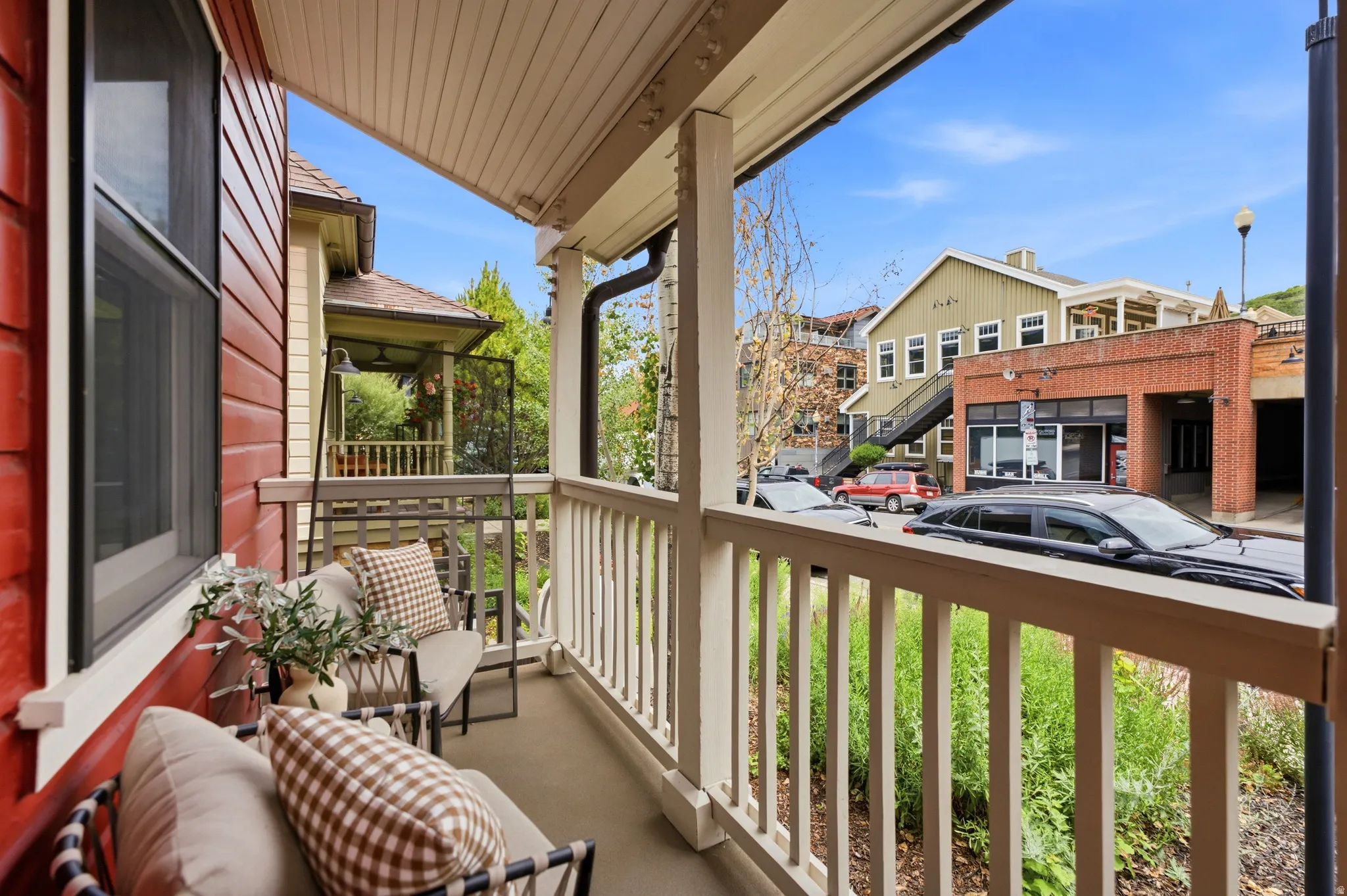 Covered balcony with a painted wood ceiling, painted wood railing, and red wood-sided exterior