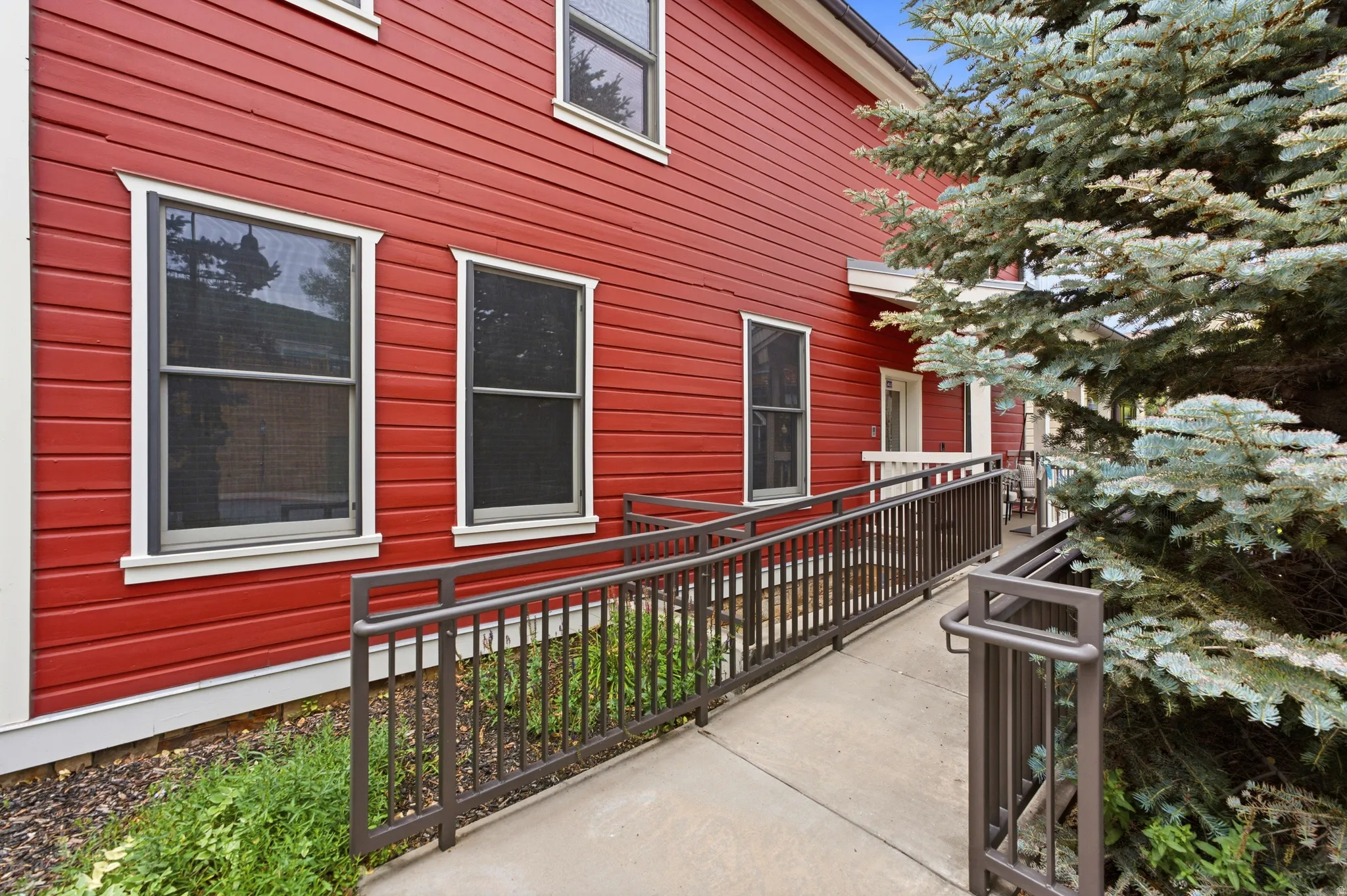 Red horizontal siding exterior with white trim windows and an accessible ramp