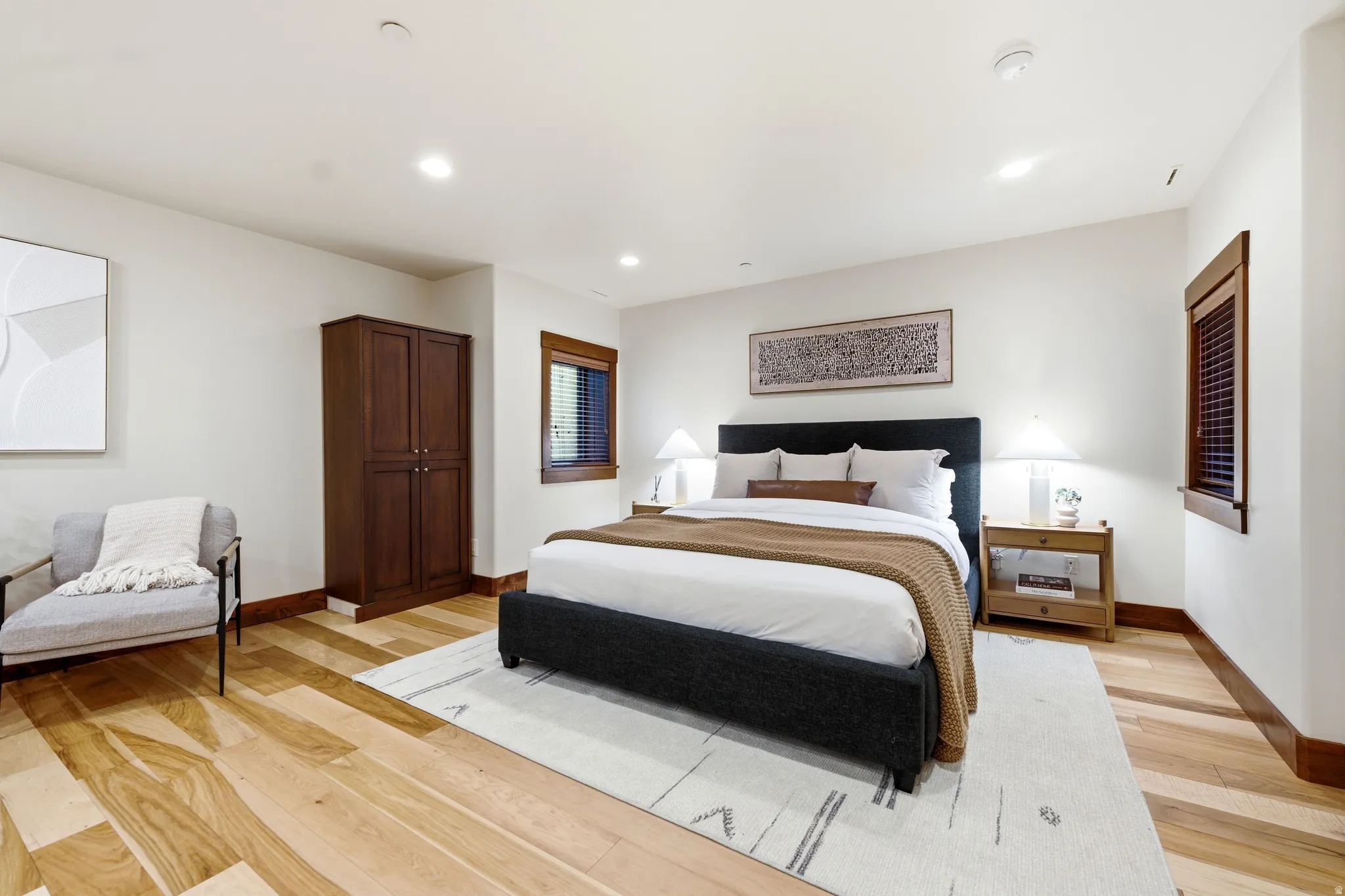 Recessed lighting, wood-finish flooring, two windows with wood trim, and a built-in wood cabinet