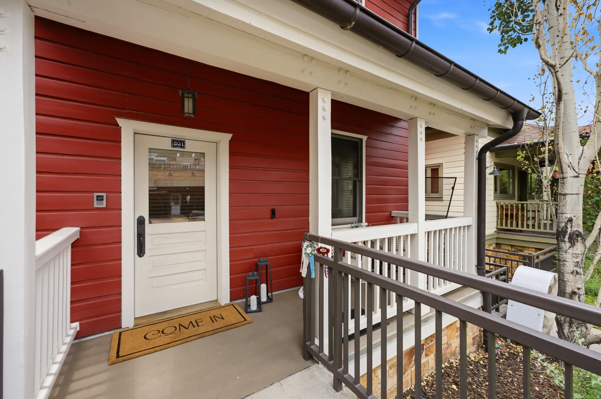 Red horizontal siding exterior with a white trim entry door featuring a transom window