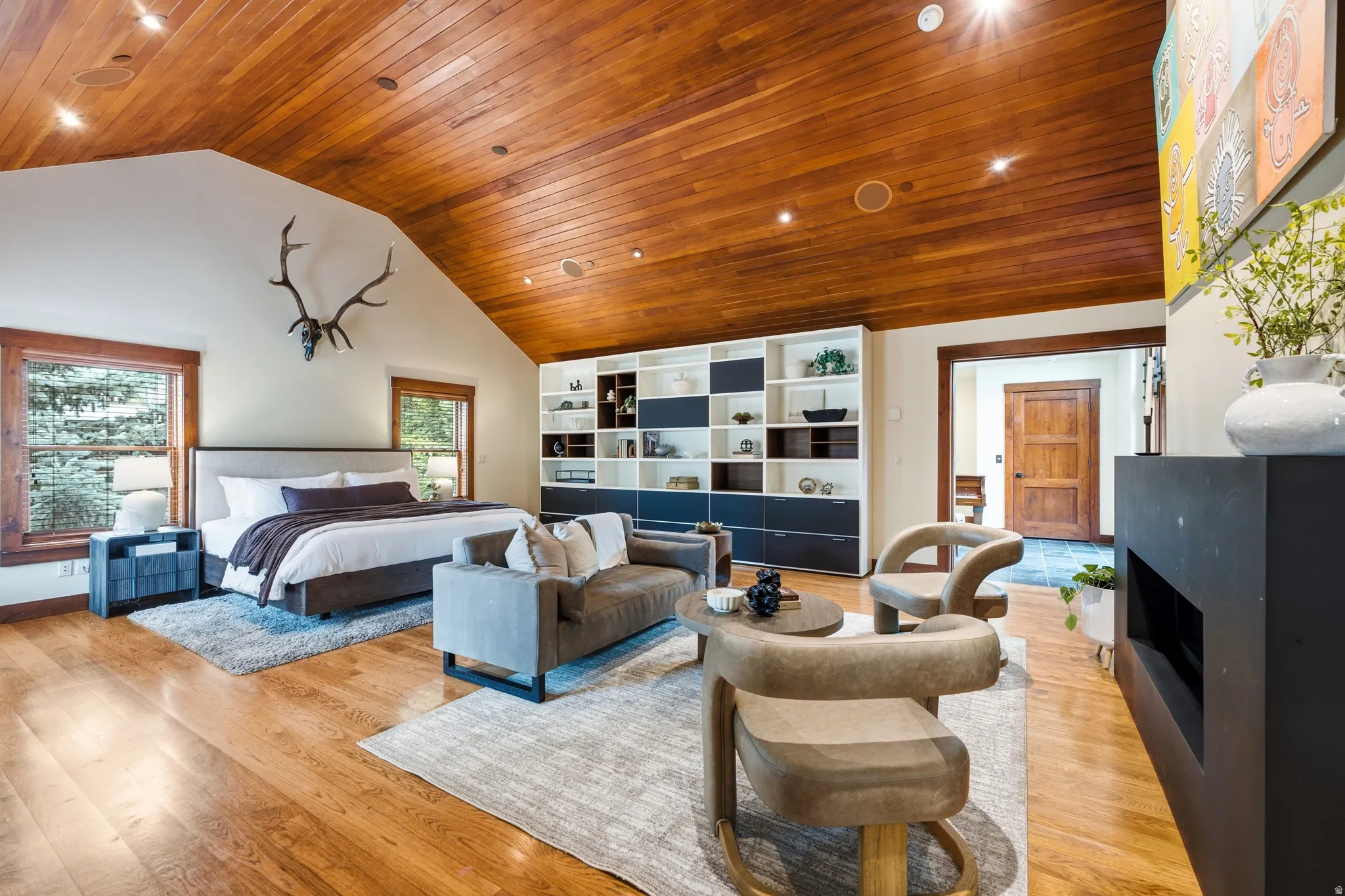 Vaulted wood-paneled ceiling, wood-finish flooring, built-in shelving, two windows, and a built-in fireplace