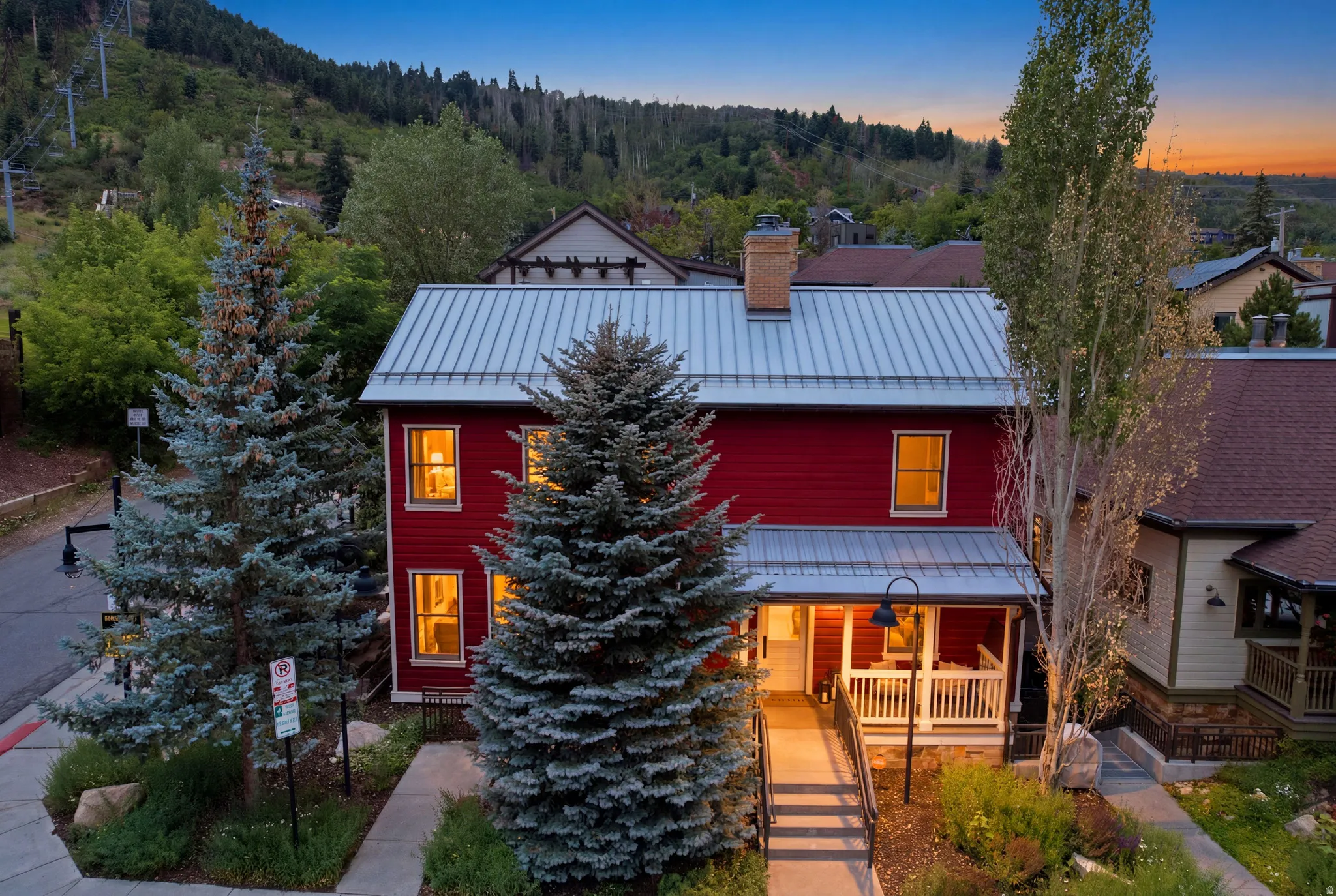 Red exterior with white trim, metal roof, and a covered front porch featuring white railings