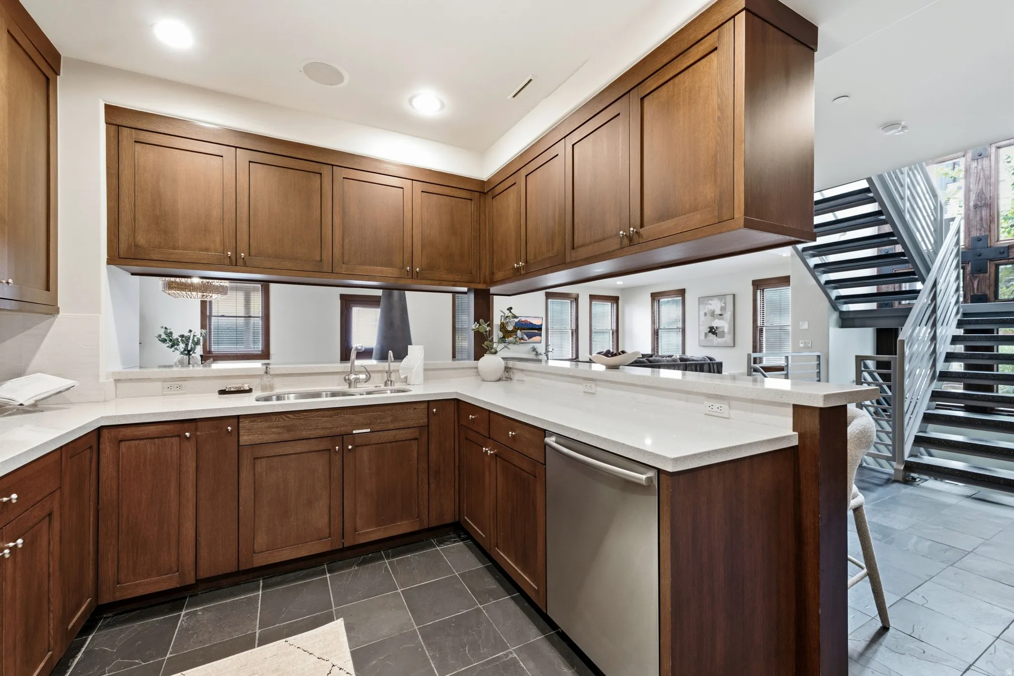 Kitchen featuring wood cabinetry, white countertops, stainless steel appliances, and dark tile flooring