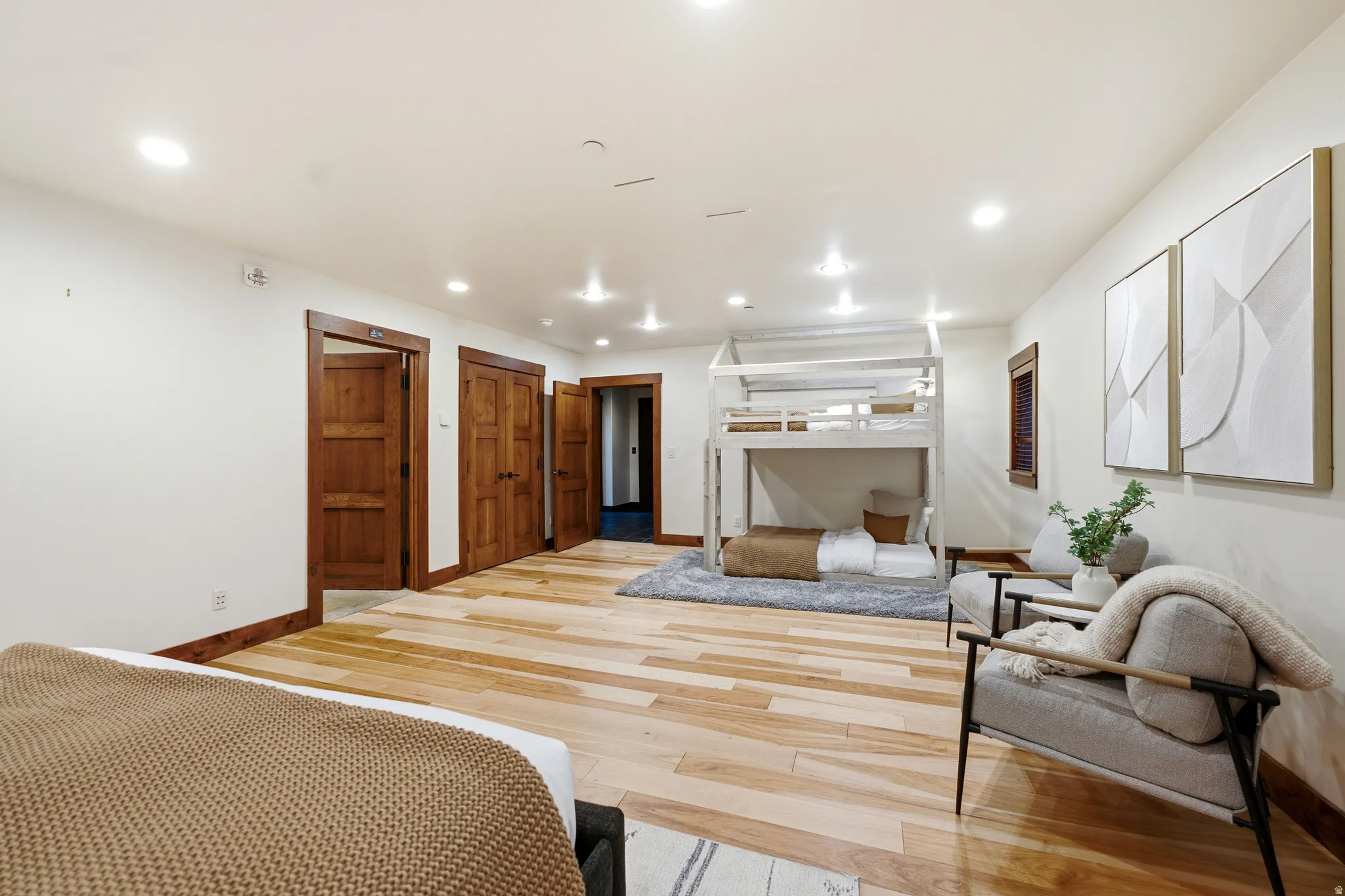 Spacious room featuring light wood-finish flooring, recessed lighting, and multiple wood doors with coordinating trim