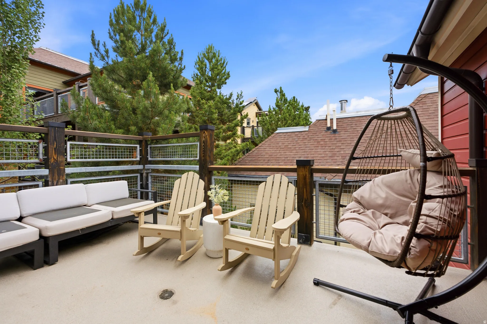 Outdoor deck with wood and metal railing, concrete flooring, and red exterior siding