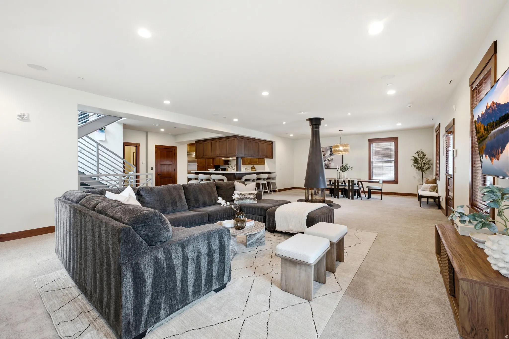 Open-concept living space featuring a freestanding fireplace, recessed lighting, and wood-finish trim