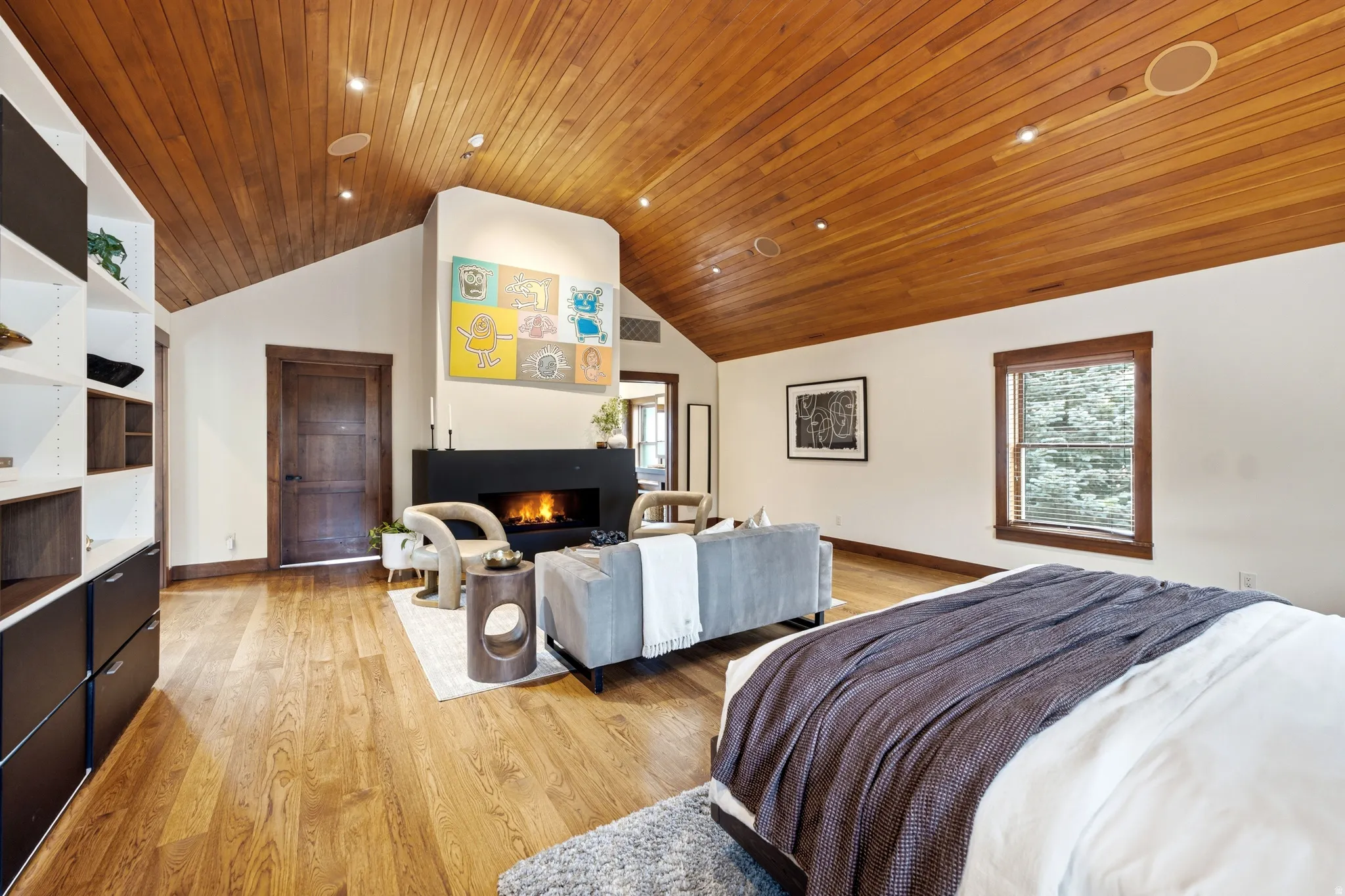 Vaulted wood-paneled ceiling, wood-finish flooring, built-in fireplace, built-in shelving, and wood-trimmed window