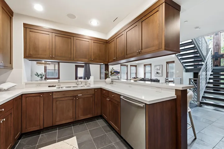 Kitchen featuring wood cabinetry, white countertops, stainless steel appliances, and dark tile flooring