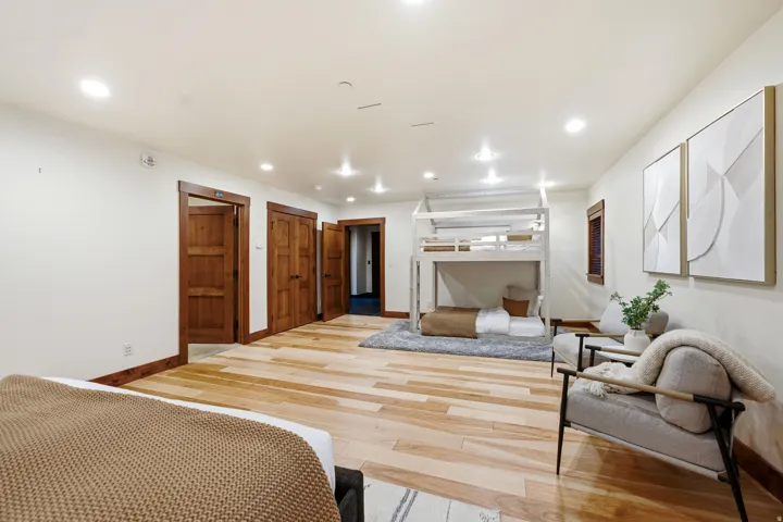 Spacious room featuring light wood-finish flooring, recessed lighting, and multiple wood doors with coordinating trim