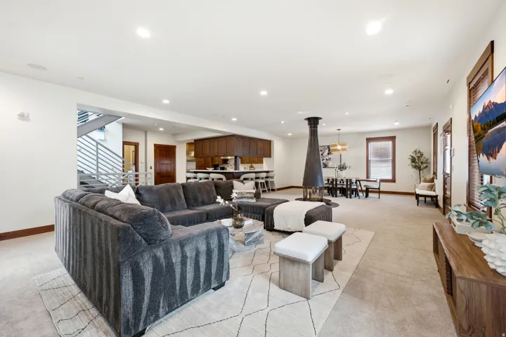 Open-concept living space featuring a freestanding fireplace, recessed lighting, and wood-finish trim