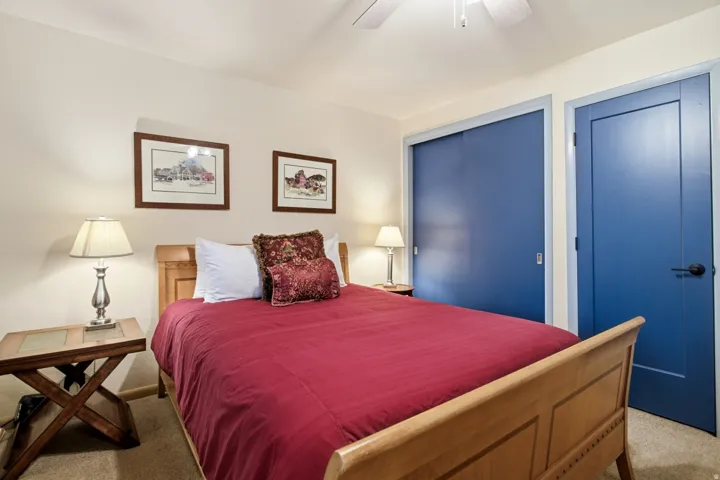 Ceiling fan with light fixture, two panel doors with matte black hardware, and sliding closet doors