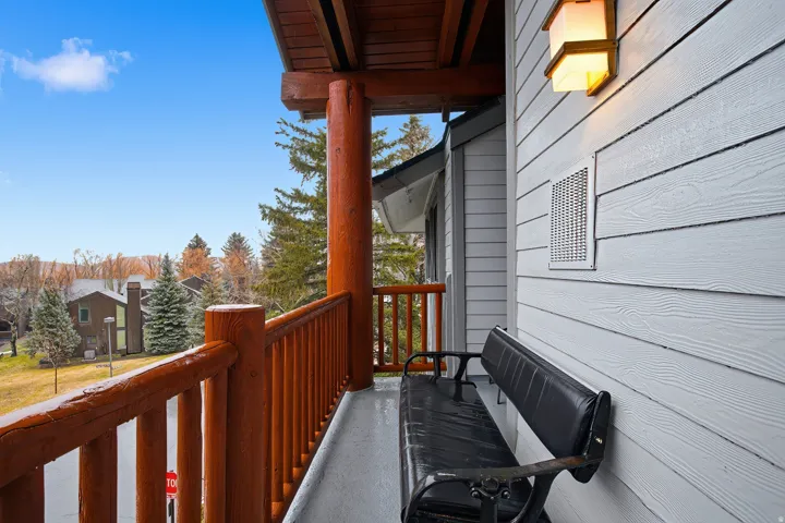 Balcony featuring rustic log railing and support pillars