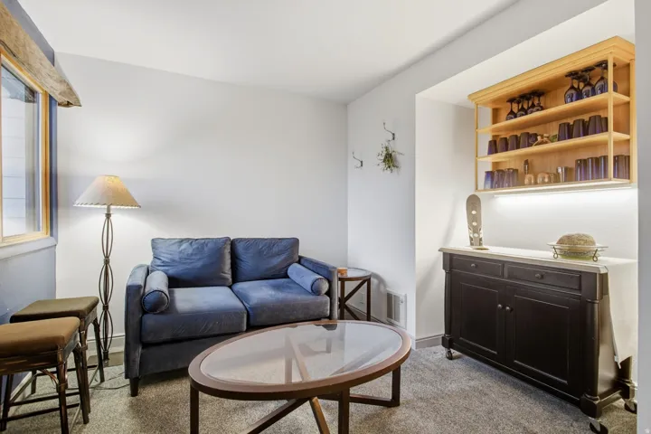 Built-in shelving with integrated lighting, wood-finish window trim, carpet flooring, and white painted walls
