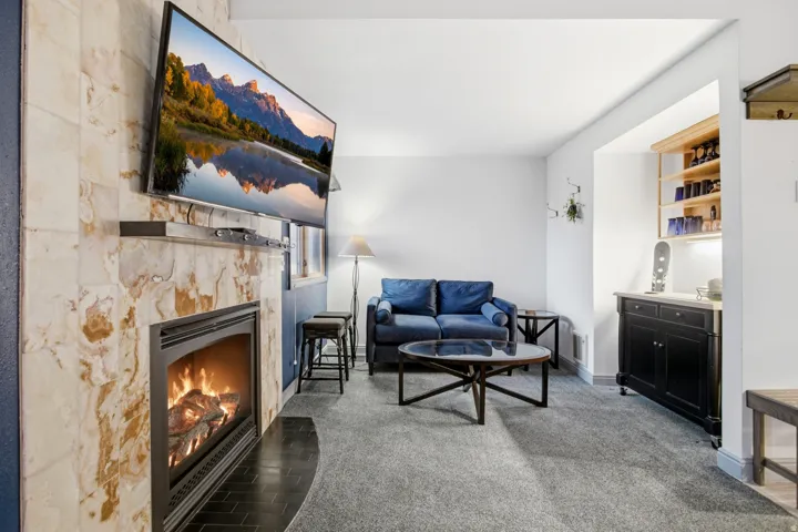 Recessed living area featuring a tile-surround fireplace, built-in shelving, carpeted flooring, and white wall finishes