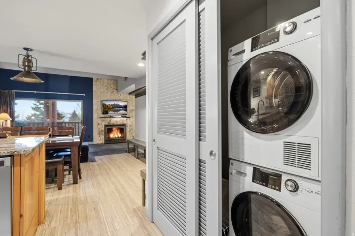 Stackable washer and dryer, wood-finish flooring, stone-clad fireplace, built-in shelving, and a large window