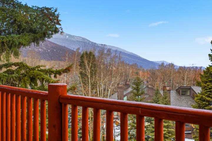 Wood-tone railing with mountain scenery and distant rooftops