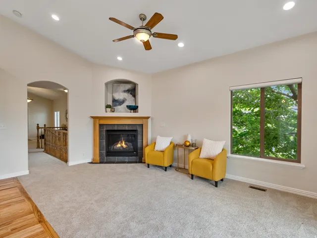 Spacious room featuring a fireplace with a wood mantel and tile surround, recessed lighting, and a ceiling fan