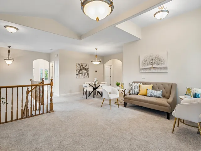 Neutral-toned carpeting throughout, tray ceiling, recessed lighting, and archways