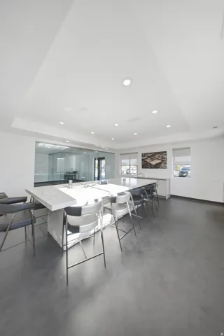 Recessed lighting, tray ceiling, dark-tone flooring, light-tone walls, and a large central table