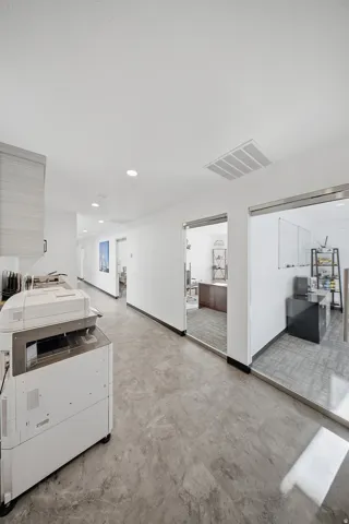 Hallway featuring recessed lighting, light gray flooring, and glass-paneled office entries