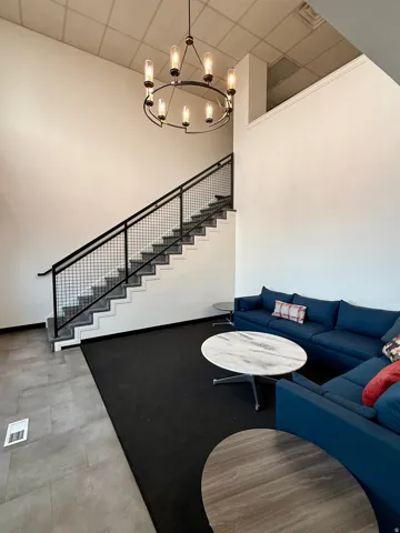 Two-story volume with a prominent staircase featuring a mesh railing and a contemporary chandelier