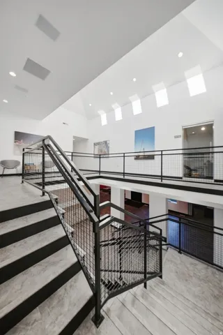 Vaulted ceilings with multiple skylights, recessed lighting, and a multi-level layout with industrial-style railings