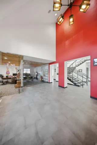 High vaulted ceilings, modern chandelier, polished concrete flooring, glass-enclosed office space, and a multi-level staircase with metal railings