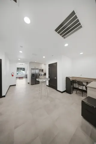Recessed lighting, light-toned tile flooring, white walls, black interior doors, and a built-in countertop with seating