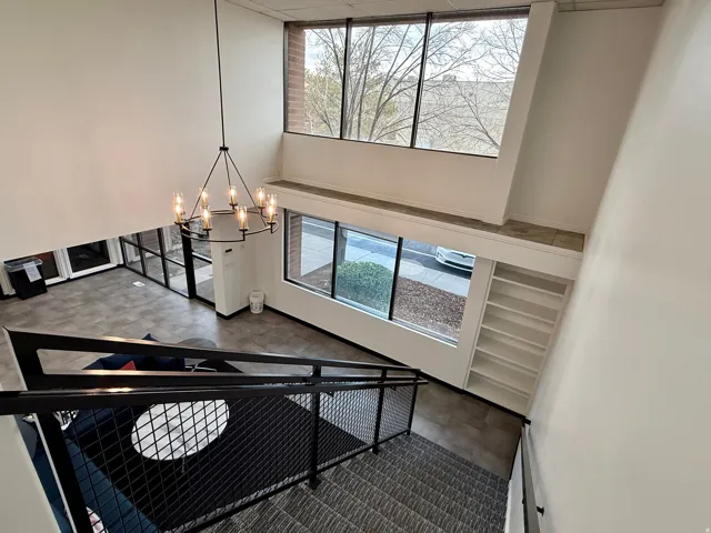 Two-story entry with a modern chandelier, large windows providing natural light, a built-in bookshelf, and open-tread stairs with a metal railing
