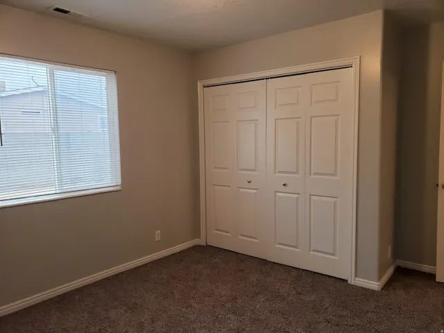 Wall-to-wall carpeting, neutral wall color, and a window with blinds