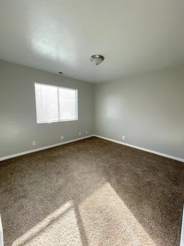 Neutral wall finishes, carpeted flooring, window with blinds, and a semi-flush mount ceiling fixture