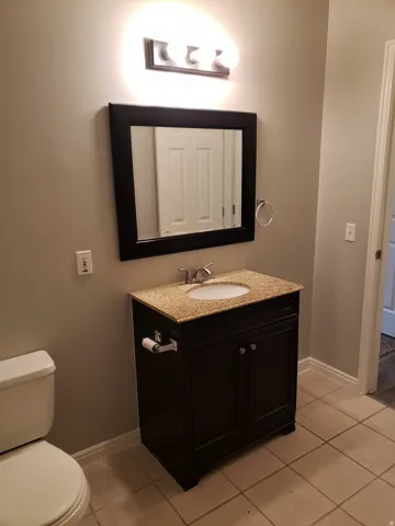 Bathroom featuring a dark wood-finish vanity with a granite-look countertop, integrated sink, and brushed nickel faucet