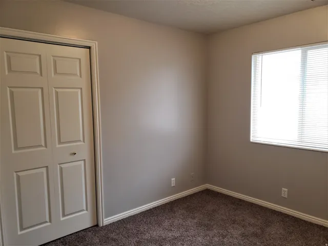 Neutral wall color, window with blinds, bi-fold closet doors, wall-to-wall carpeting, and white trim