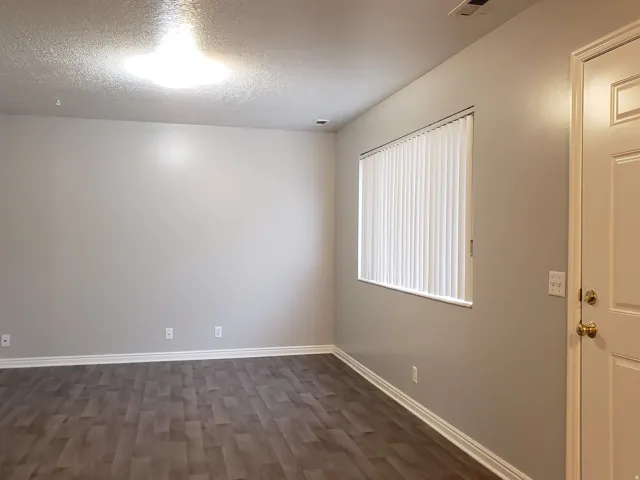 Recessed ceiling light fixture, neutral wall paint, wood-finish flooring, window with vertical blinds, and a paneled entry door