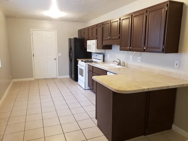 Kitchen featuring a built-in dishwasher, a white gas range, and a white sink