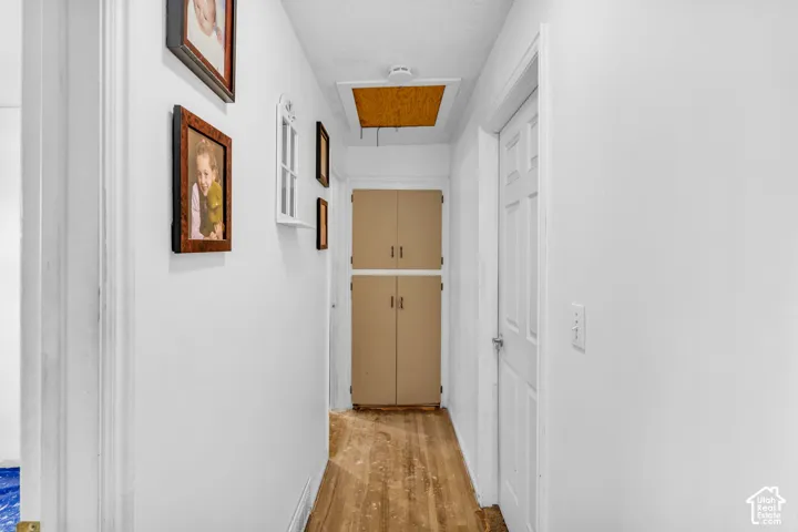 Hallway featuring wood-finish flooring, white painted walls, and built-in cabinetry