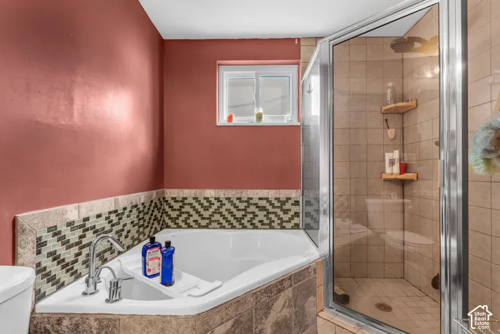Corner soaking tub with a mosaic tile surround and a tiled walk-in shower with a glass enclosure