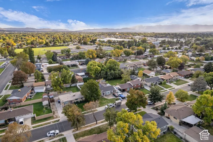 Aerial perspective showcasing a residential area with mature trees, green spaces, and mountain backdrops