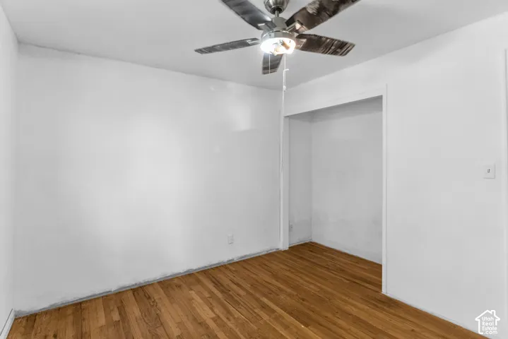 Wood-finish flooring, white walls, ceiling fan with integrated lighting, and a recessed alcove
