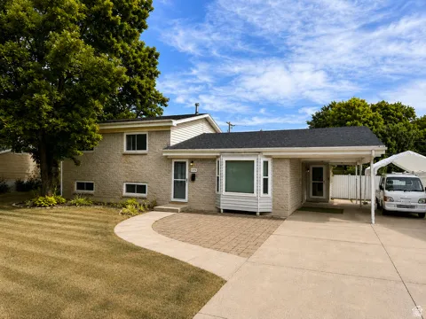 Split-level residence featuring a brick facade, paved driveway, and established landscaping