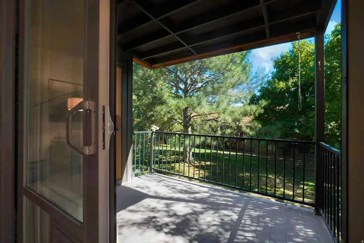 Sliding glass door leading to a private outdoor balcony with black metal railings and a wood-finish floor