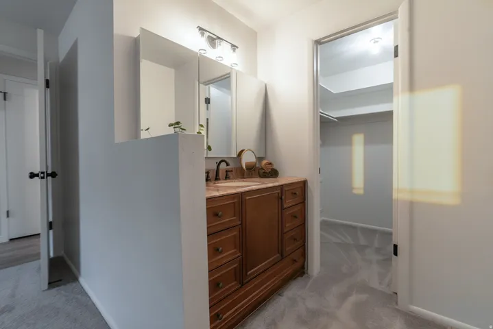 Bathroom vanity with wood-finish cabinetry, countertop, and an integrated sink with a dark-finish faucet