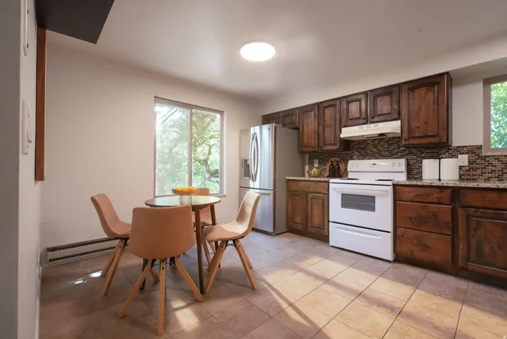 Kitchen featuring wood cabinetry, stainless steel refrigerator, white range, tile flooring, and a tiled backsplash