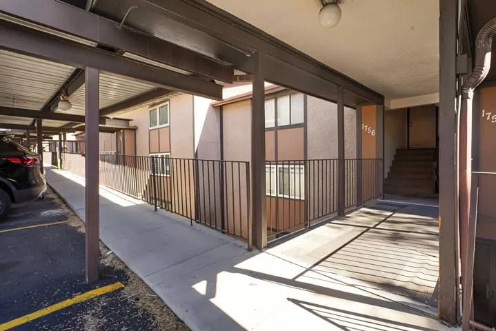 Covered parking structure with designated parking spaces, exterior railings, and an accessible ramp