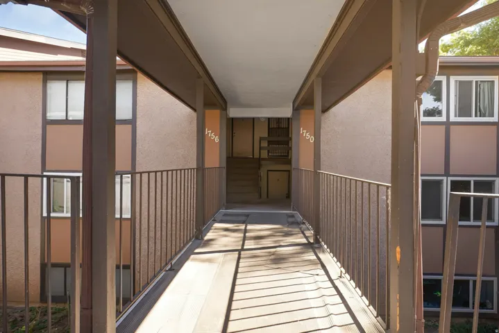 Exterior walkway featuring a metal railing and architectural support columns