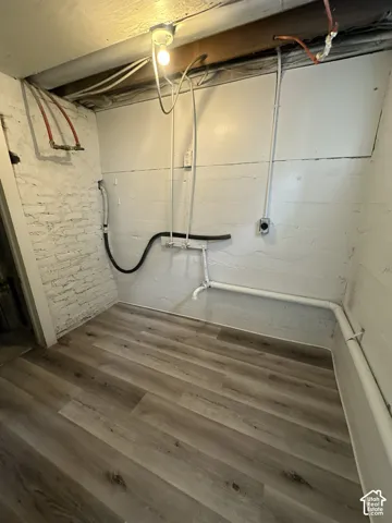 Wood-finish flooring with a white brick wall and exposed ceiling joists