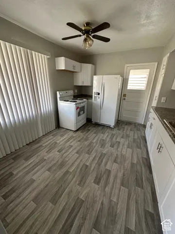 Kitchen featuring wood-finish flooring, white cabinetry, a ceiling fan with integrated lighting, and a door with louvered glass