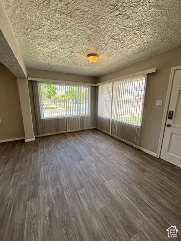Room with wood-finish flooring, multiple windows, and a flush-mount ceiling light