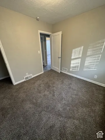 Neutral tone wall paint, dark tone carpet flooring, white trim, and a white panel door