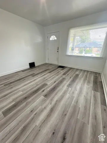 Wood-finish flooring throughout, bright white walls, and a window with horizontal blinds